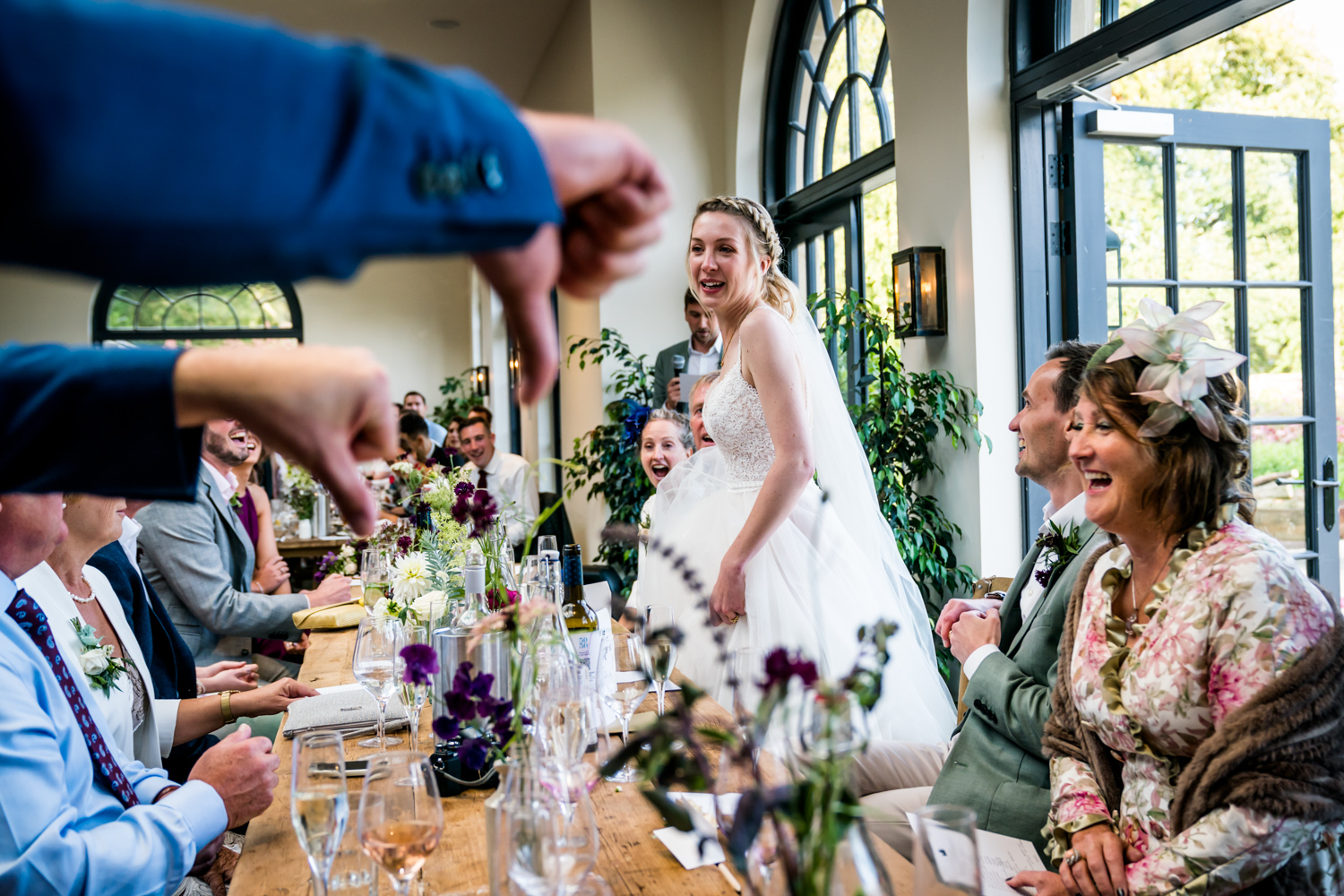 Bride laughing joyfully during a wedding toast as guests look on.