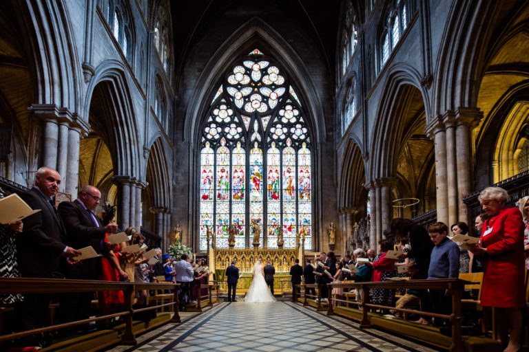 A wedding ceremony in a church with stained glass windows.
