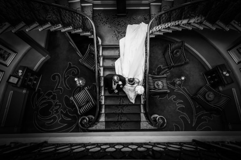 A black and white photo of a bride and groom on a staircase at their wedding ceremony.