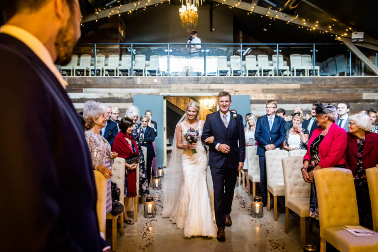 A bride and groom walking down the aisle during their ceremony at a barn wedding.