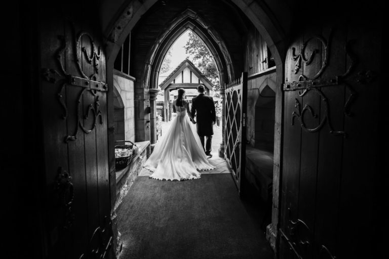 A bride and groom standing in the doorway of a church after their ceremony.