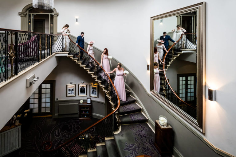 A bride and her bridesmaids are walking down a spiral staircase during the wedding ceremony.