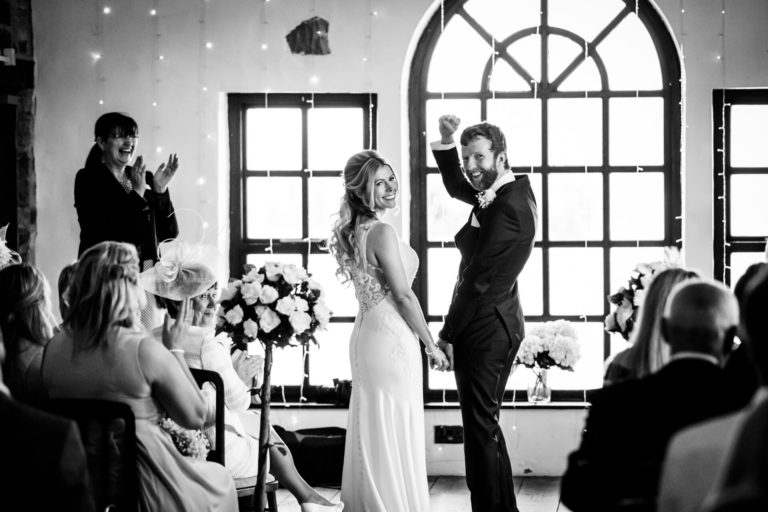 bride and groom smiling at their guests at the end of the ceremony