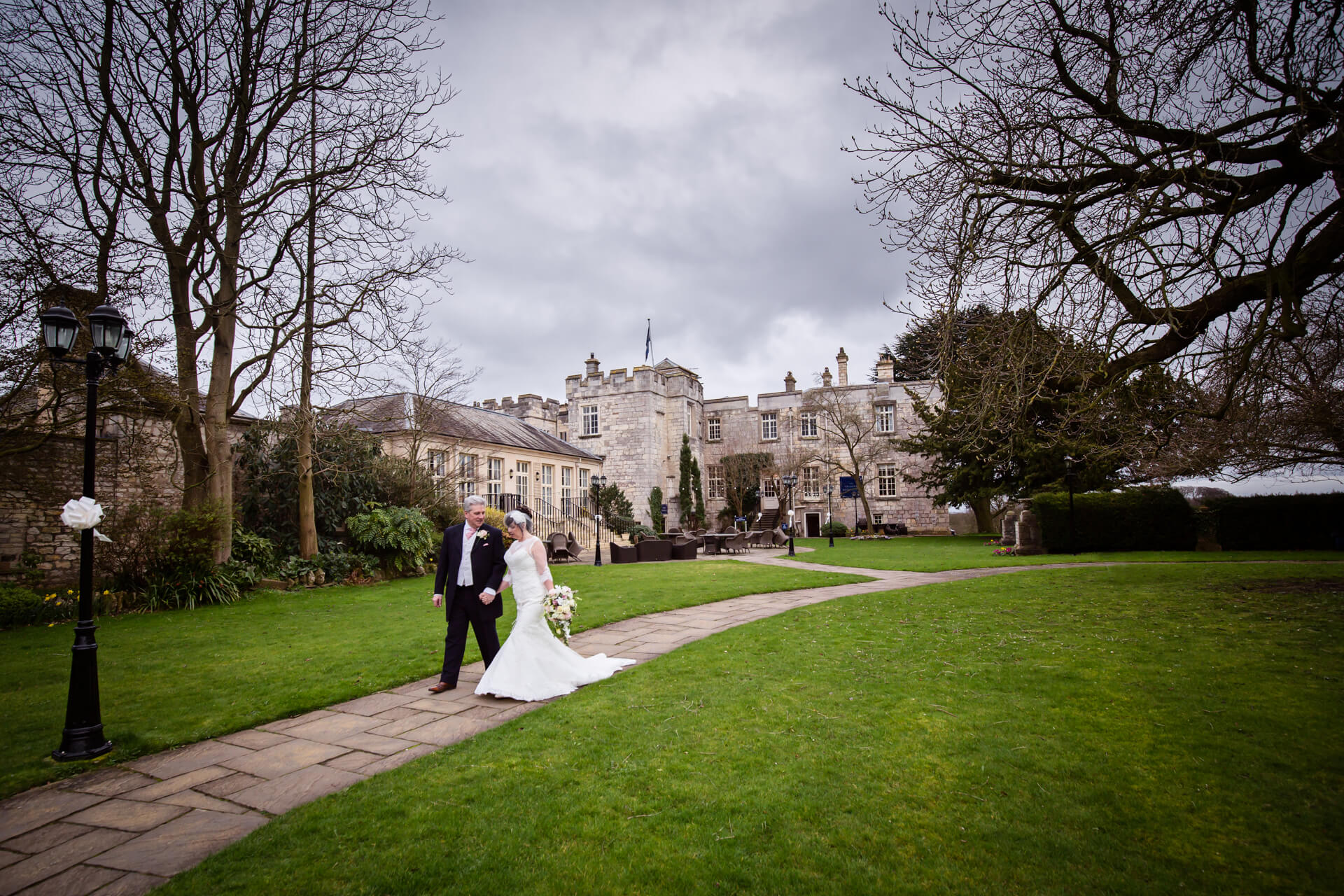 Hazlewood Castle wedding photographer - bride and groom walking in the castle grounds
