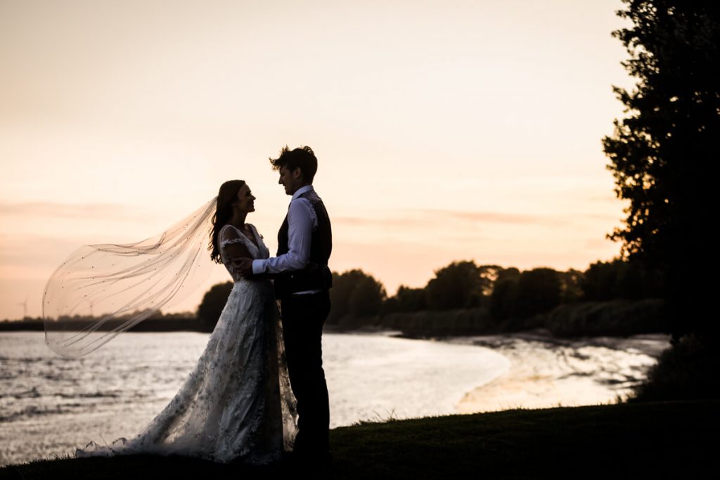 wedding couple embrace as the sun begins to set