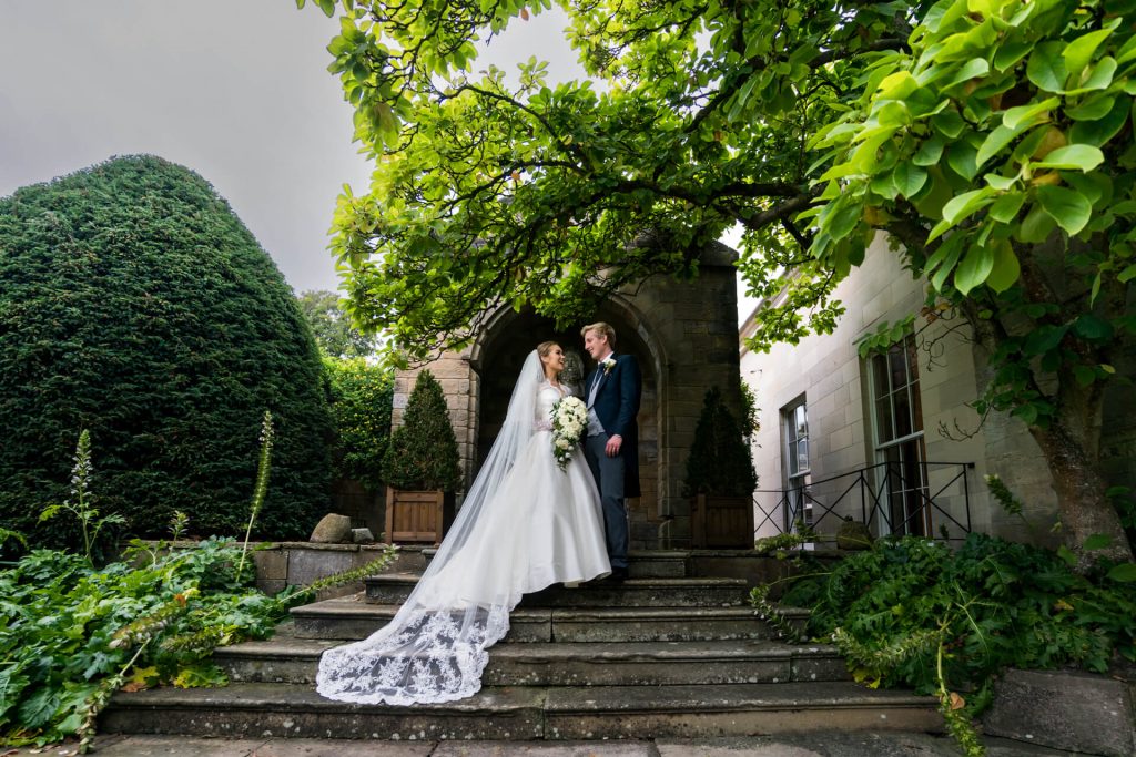 wedding couple stand together on the steps of rudding park hotel