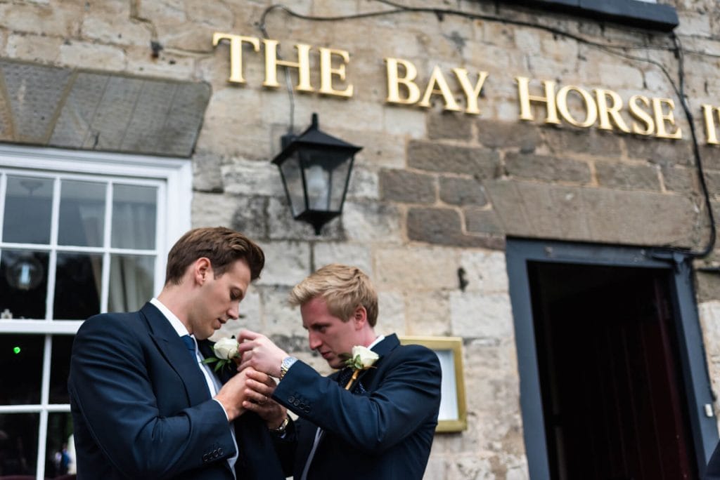 groom helping the best man with his buttonhole