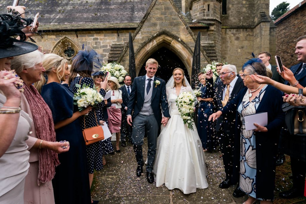 guests throw confetti over the bride and groom
