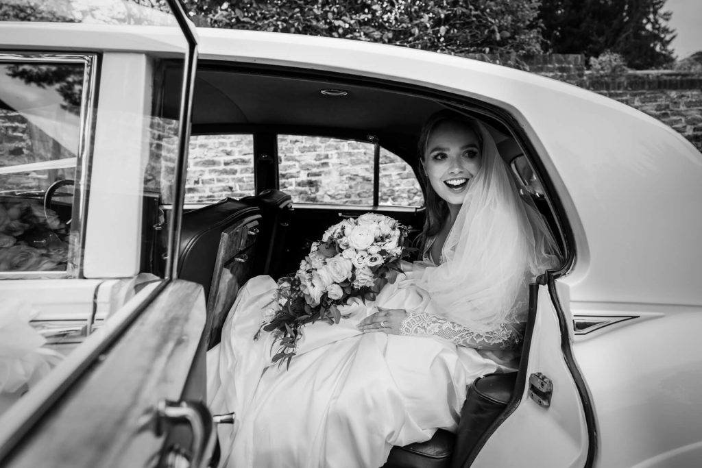 bride smiling whilst sitting in the wedding car