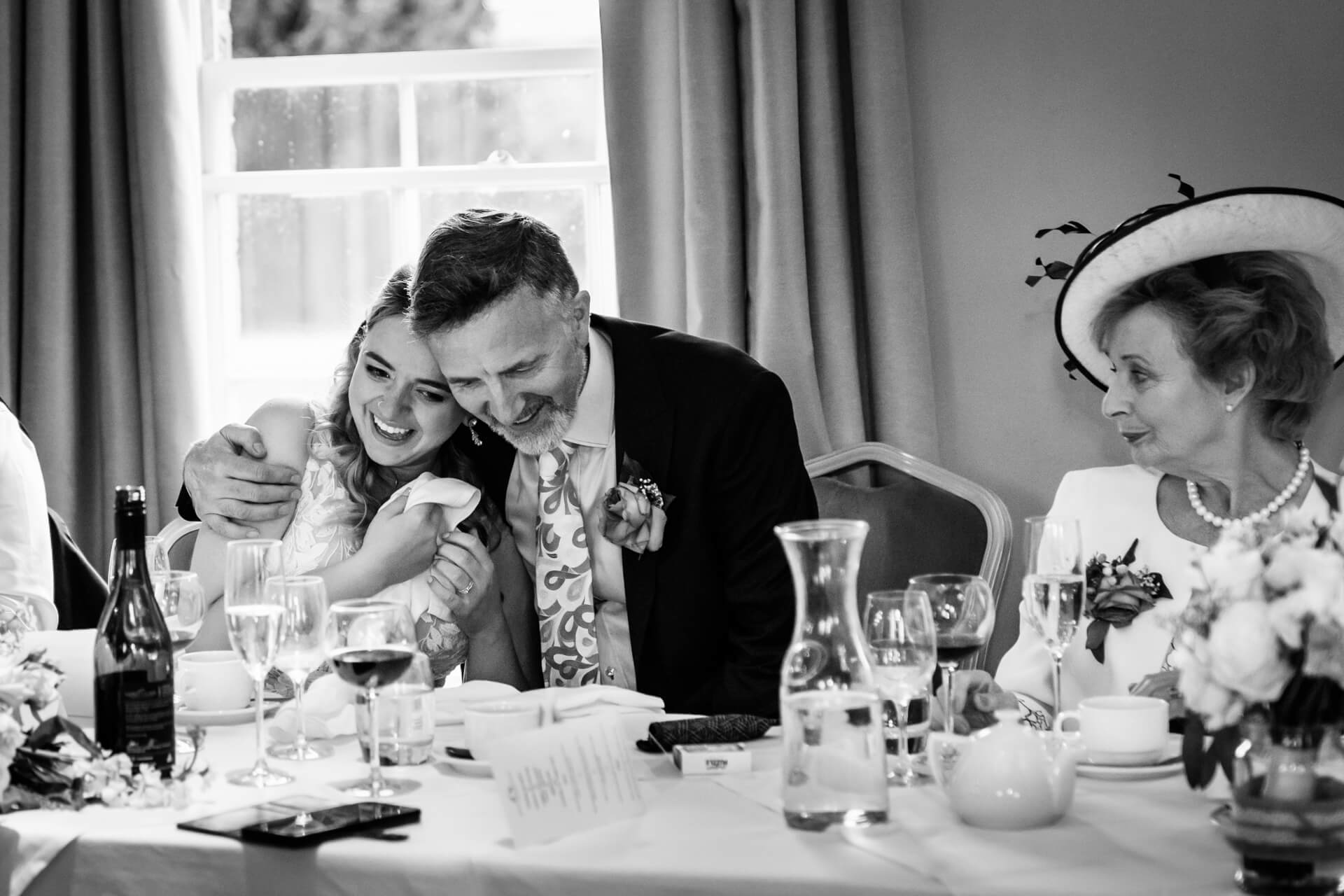 father of the bride hugs his daughter during the wedding speeches