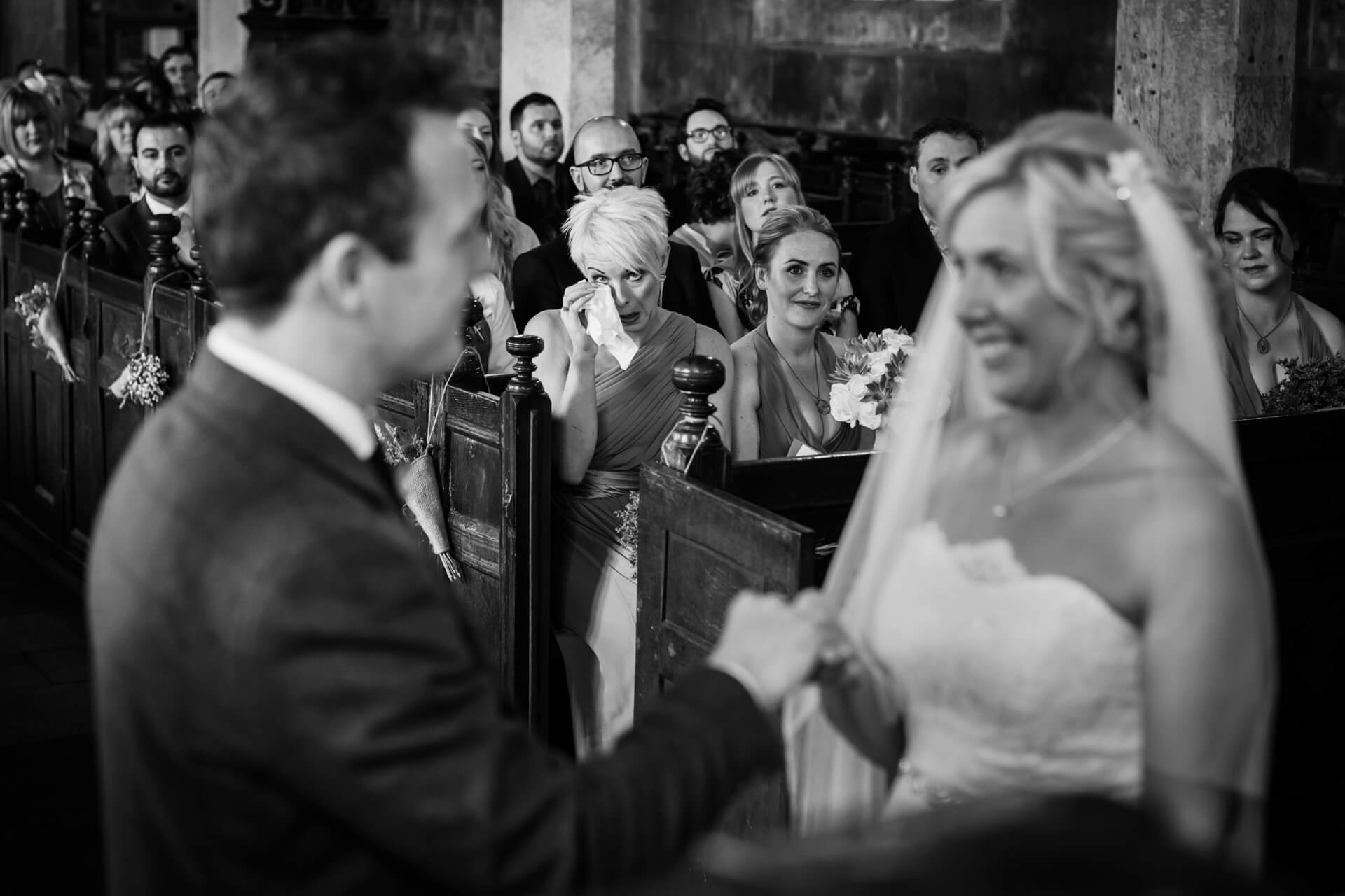 bridesmaid cries in the audience as the wedding couple take their vows