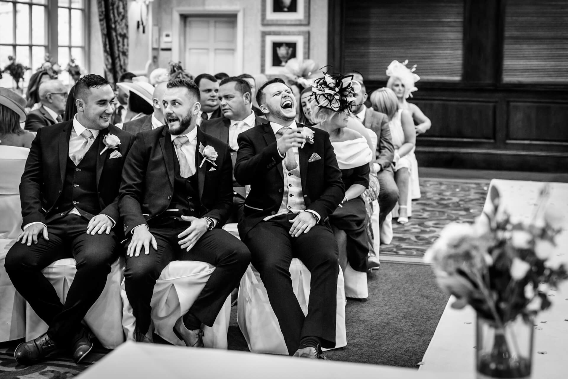 groomsmen laugh whilst waiting in the ceremony room at Woodhall Hotel