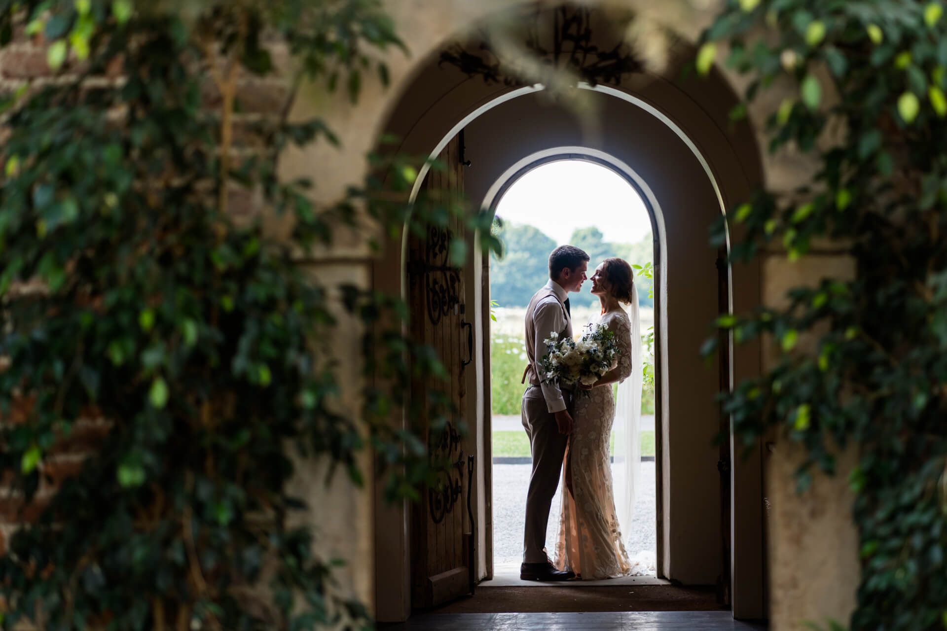 bride and groom standing together under an archway at Middleton Lodge