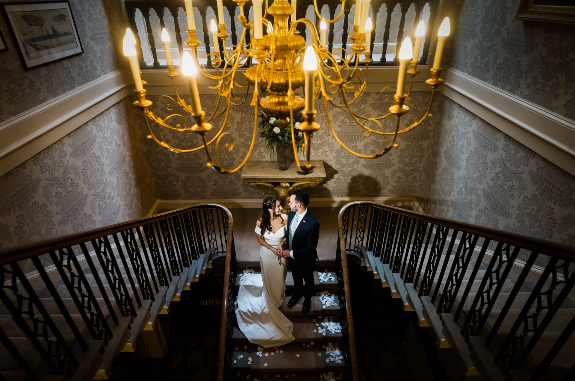bride and groom holding hands under a chandelier at Bowcliffe Hall