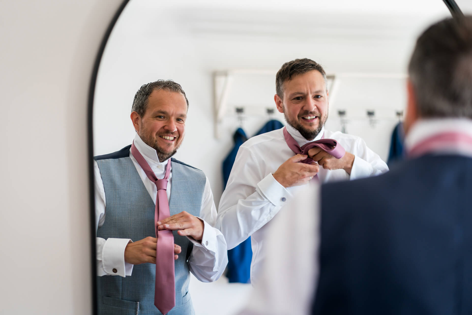 groom and best man looking in a mirror and fixing their ties