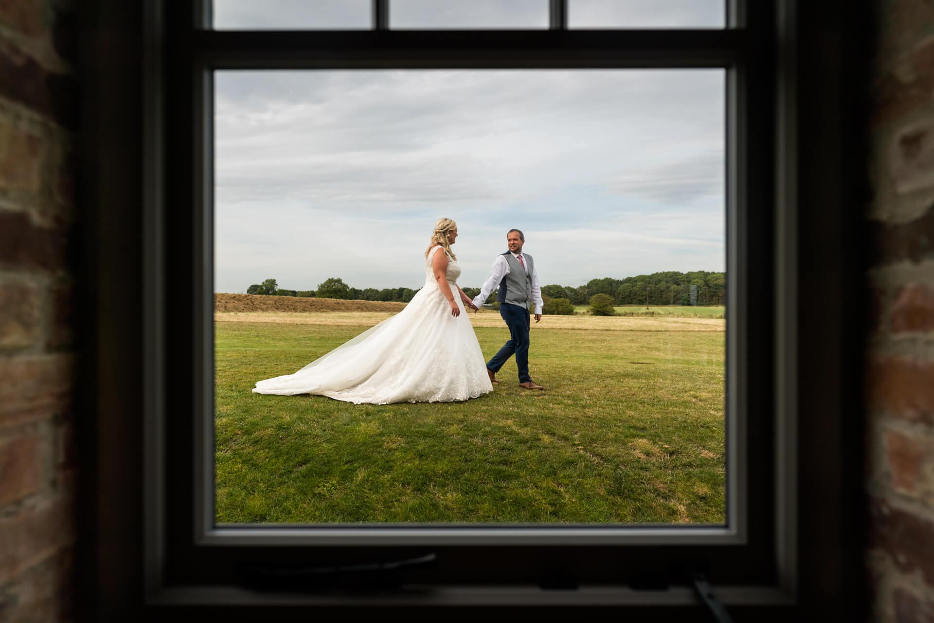 bride and groom walking in a field at Thirsk Lodge Barns