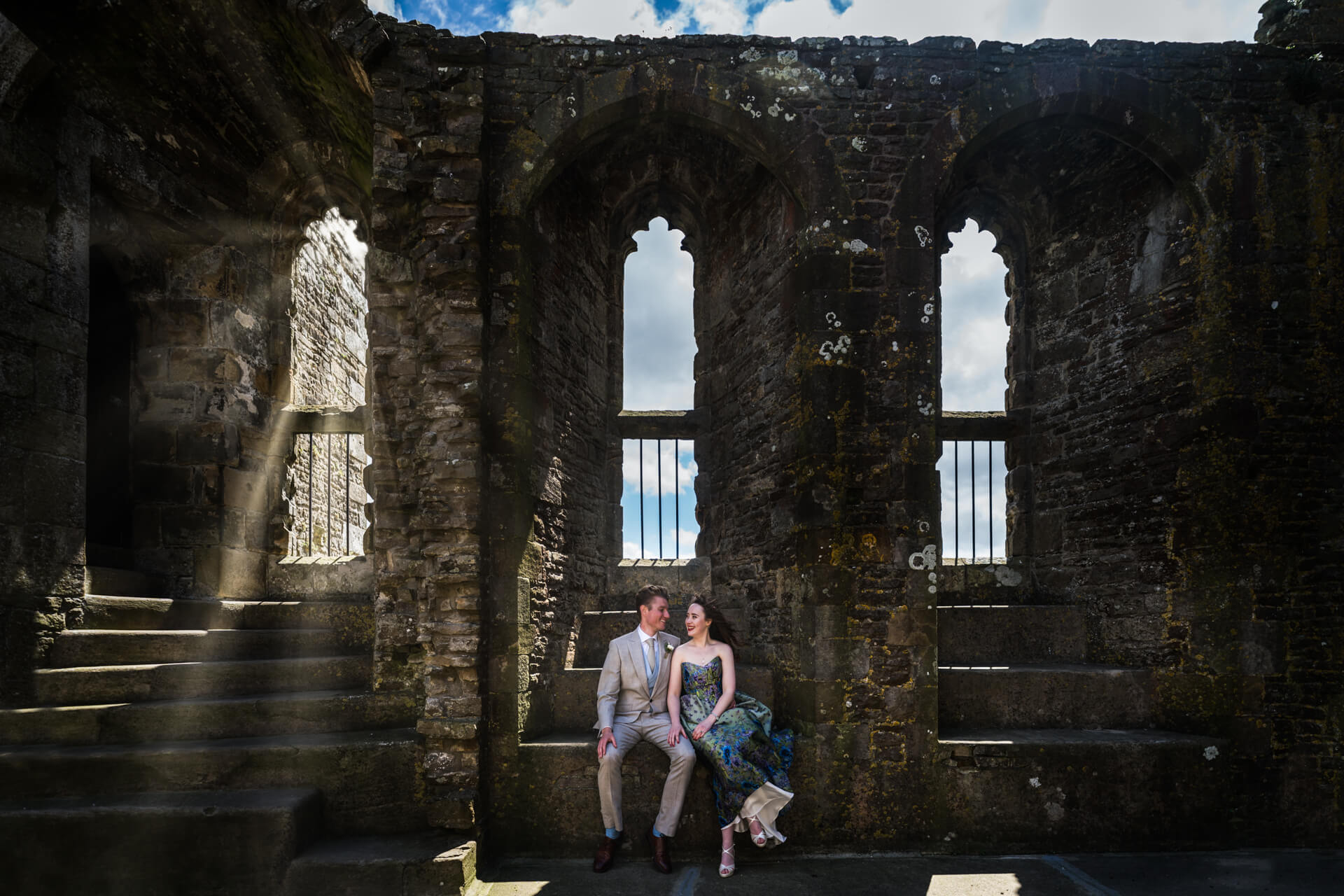 bride and groom sitting in the ruins of Bolton castle