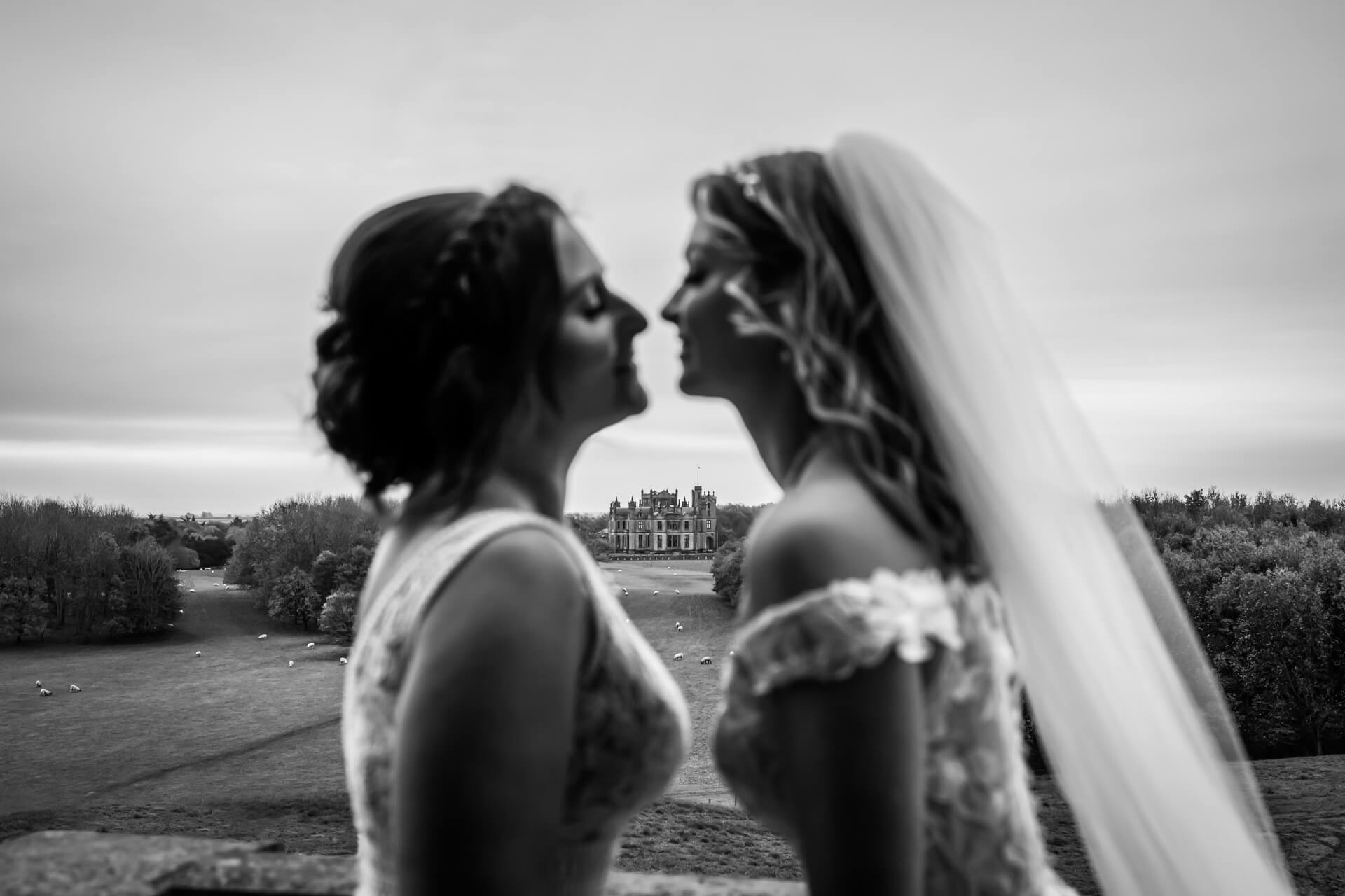 wedding couple kiss in front of a view of Allerton castle