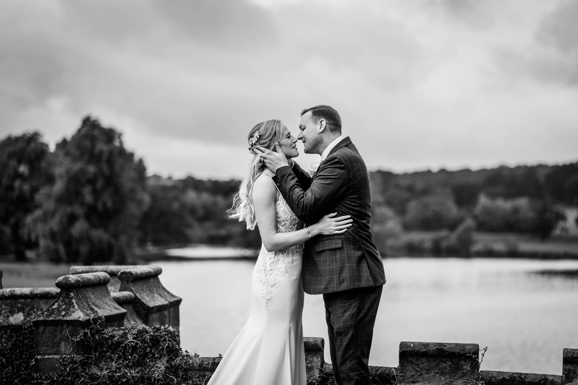 bride and groom kissing in front of the lake at Ripley Castle
