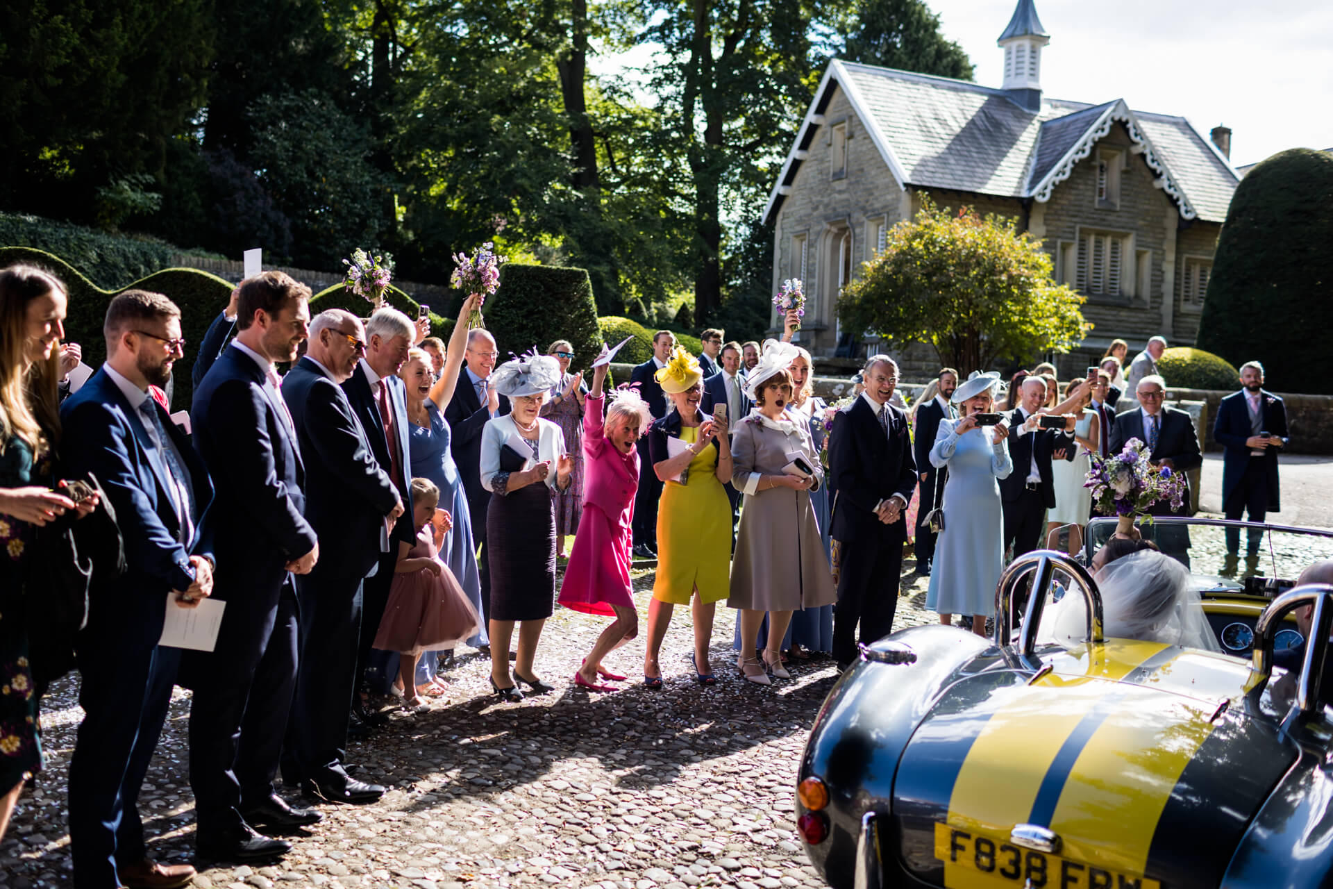 wedding guests cheer as the wedding car departs