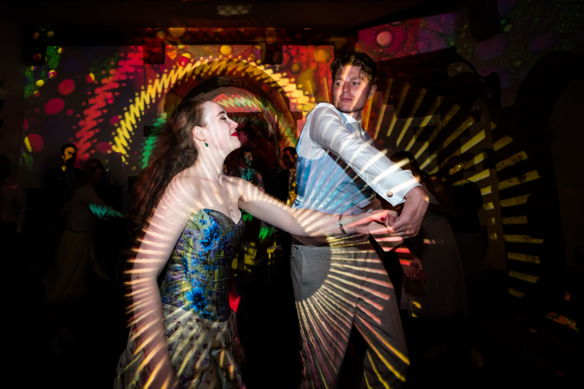 bride and groom dancing under colourful lights