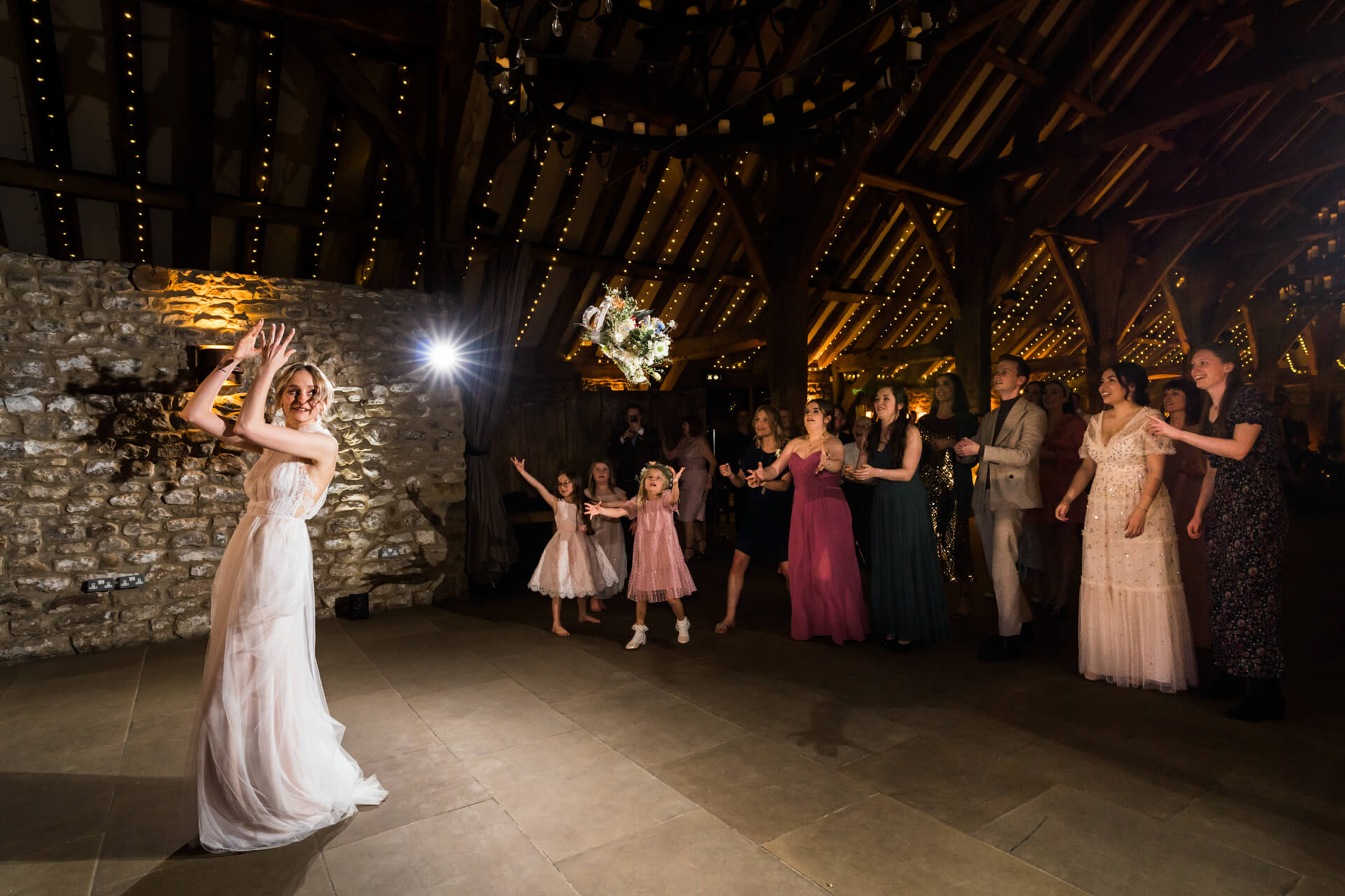 bride throwing her bouquet inside Tithe Barn