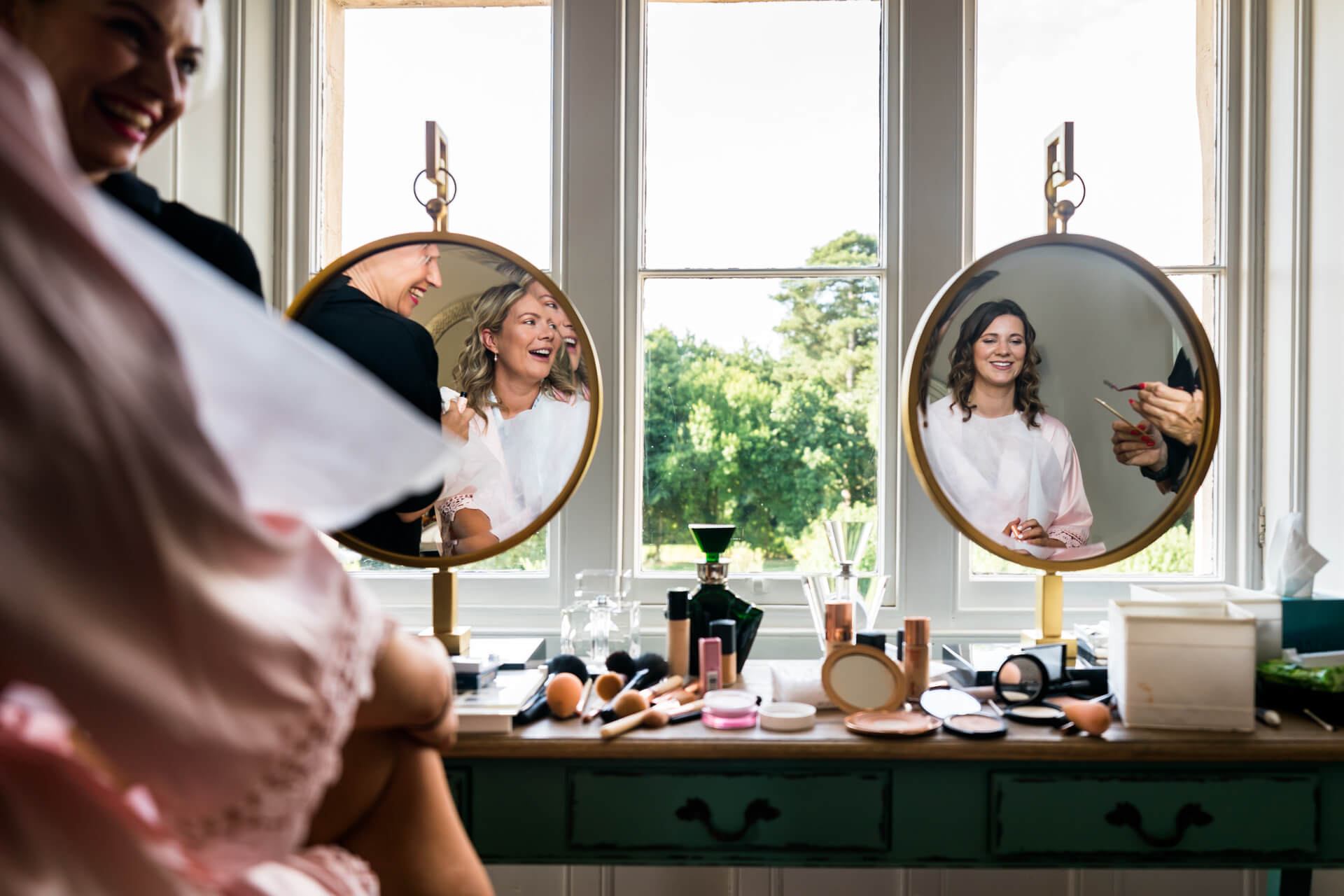 bridesmaids reflected in two mirrors whilst having their makeup done