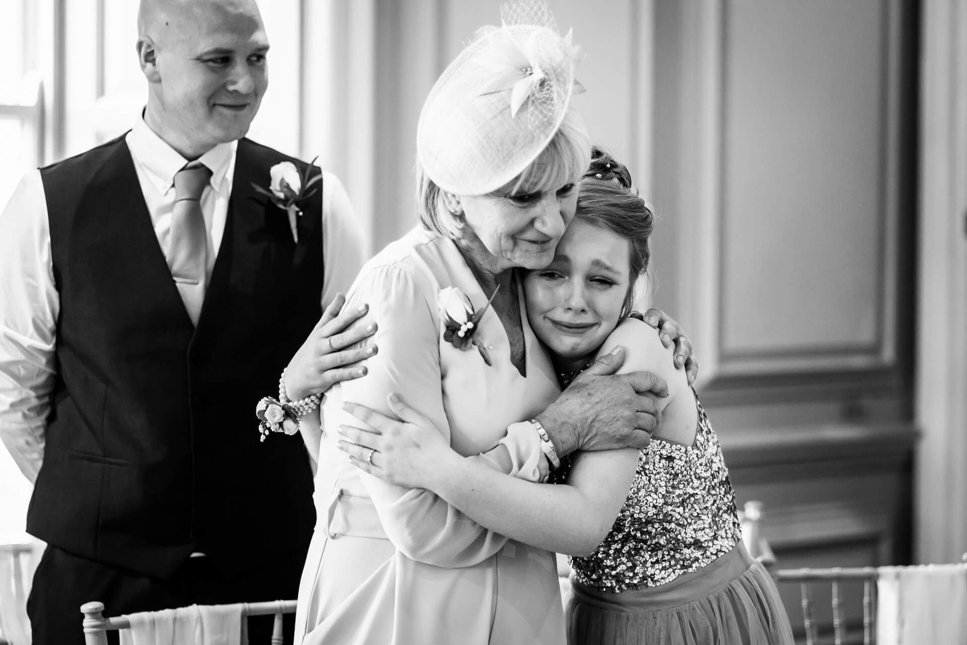 bridesmaid cries during the ceremony whist grandma hugs her