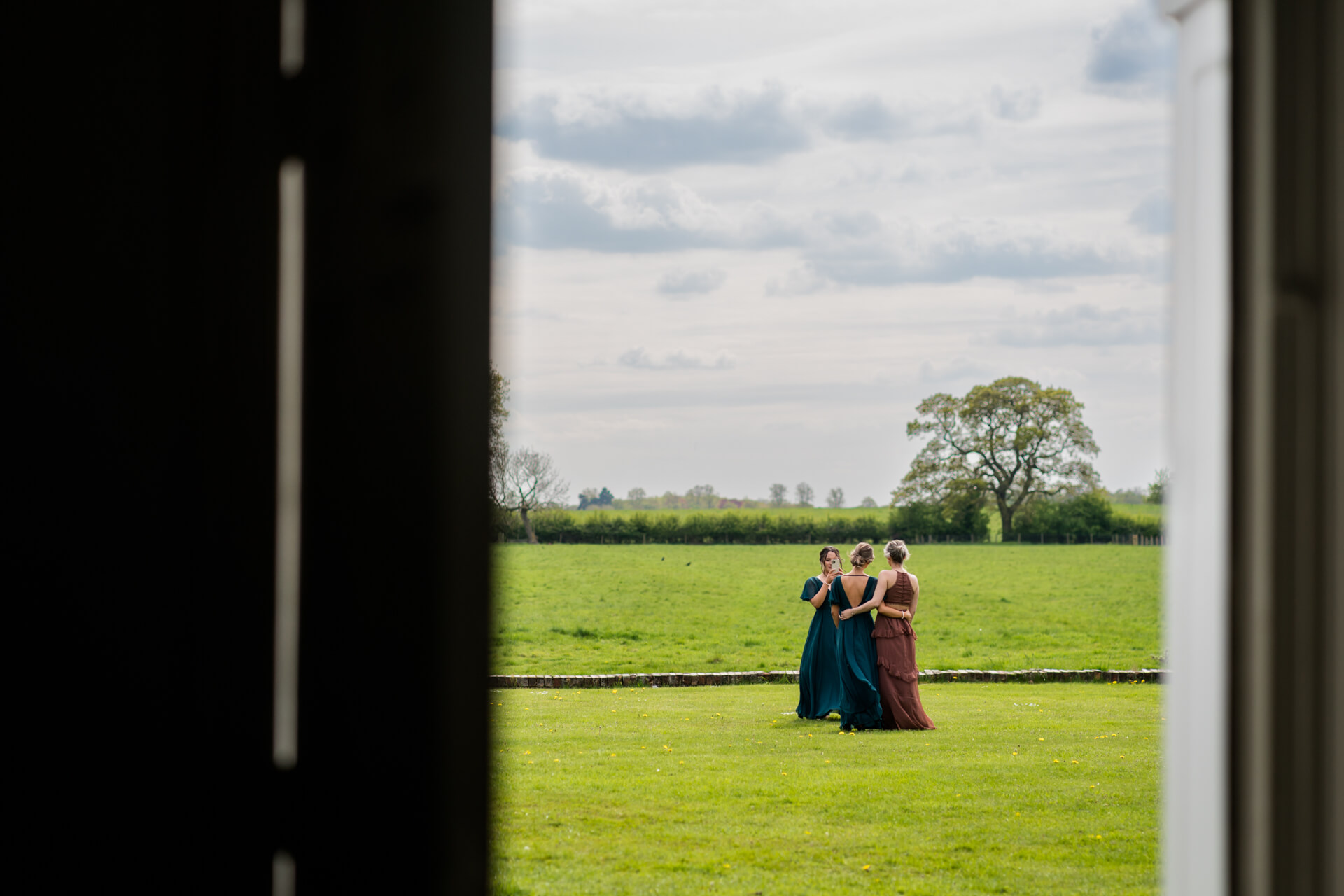 bridesmaids take photos of each other on the lawns at Mornington Manor
