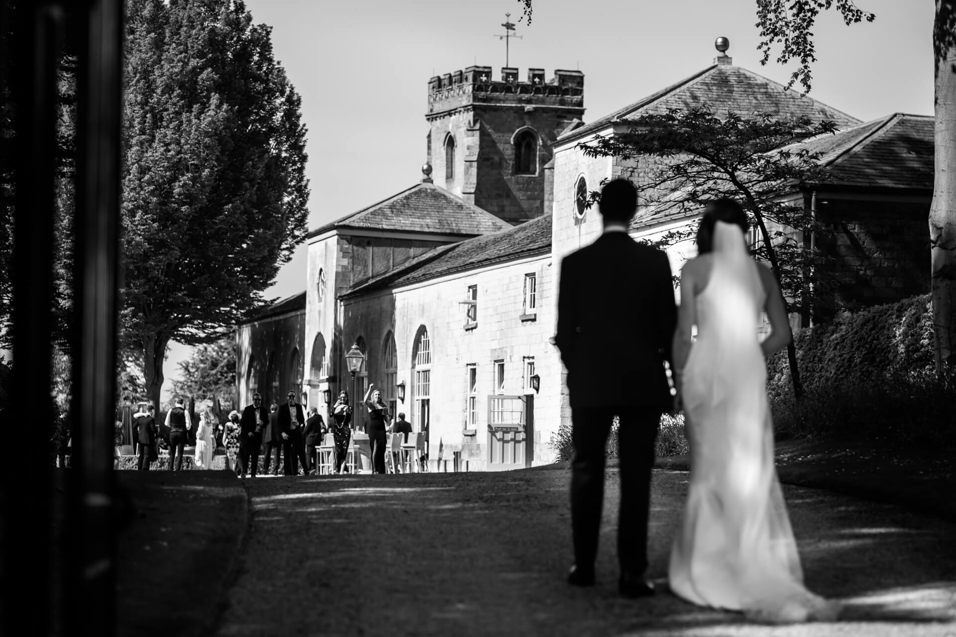 bride and groom walk up to their guests waving outside the orangery at setrrington