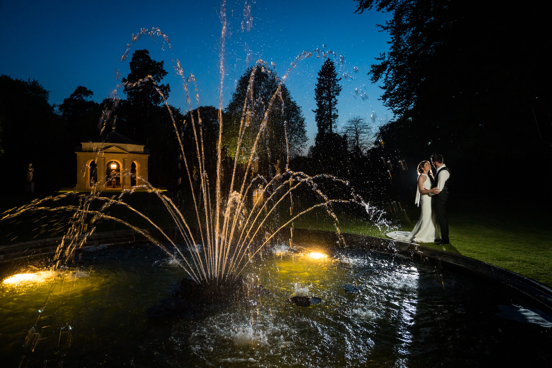 bride and groom by the fountain at night at the Orangery at Settrington