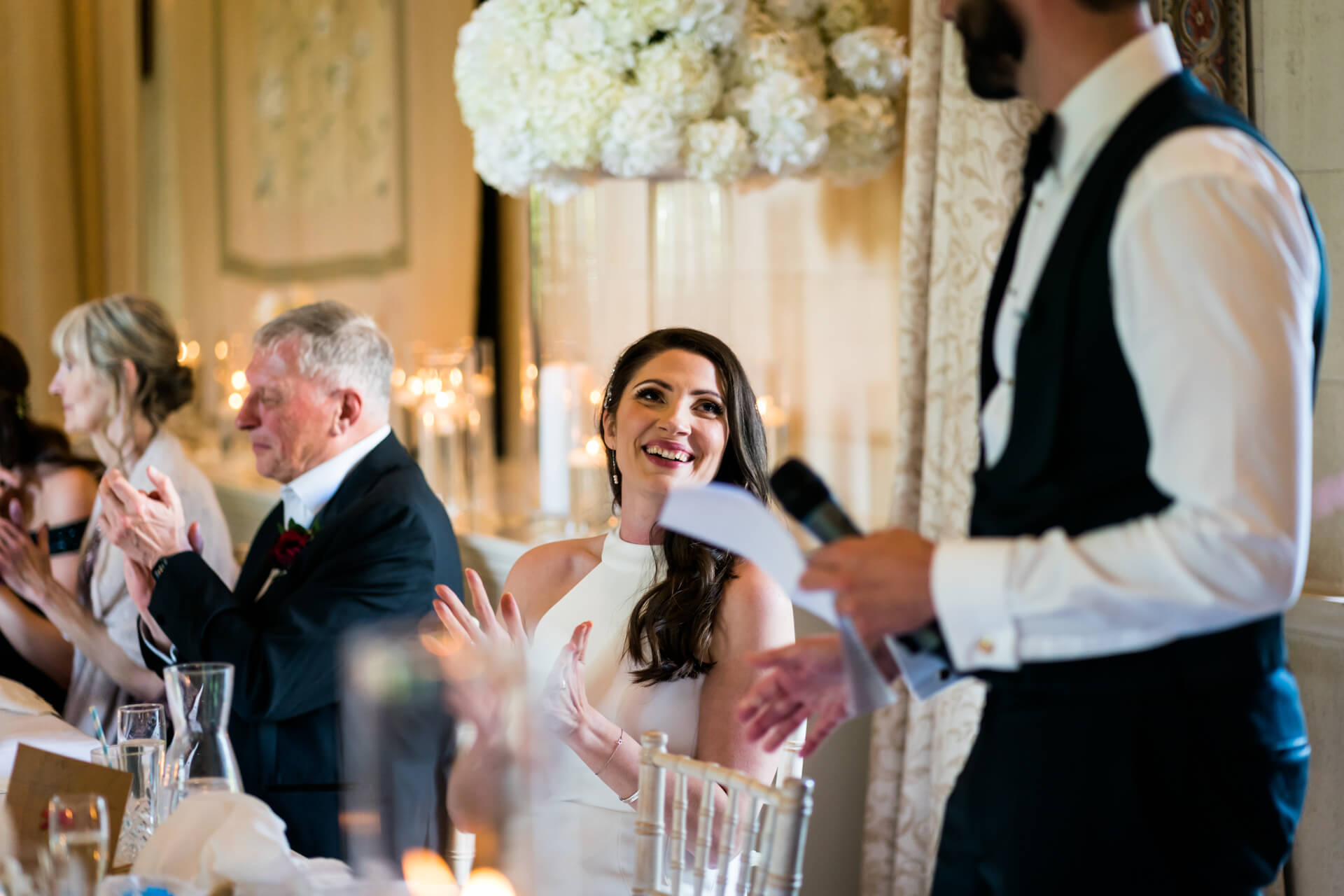 bride claps whilst her husband does his speech