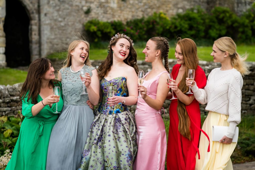 bride and her bridesmaids cheering with classes of wine