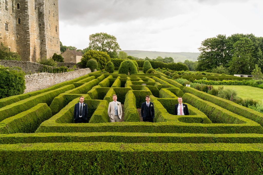 groom with groomsmen standing in the maze at Bolton Castle