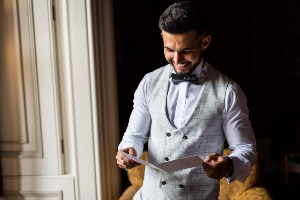 groom smiling whilst looking at a card from his bride