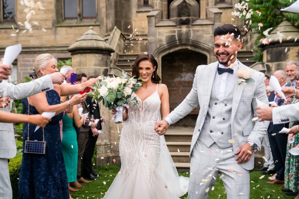 wedding couple are showered with confetti in the grounds of Allerton Castle