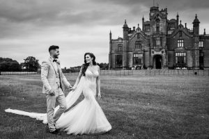 wedding couple holding hands and walking in front of Allerton Castle
