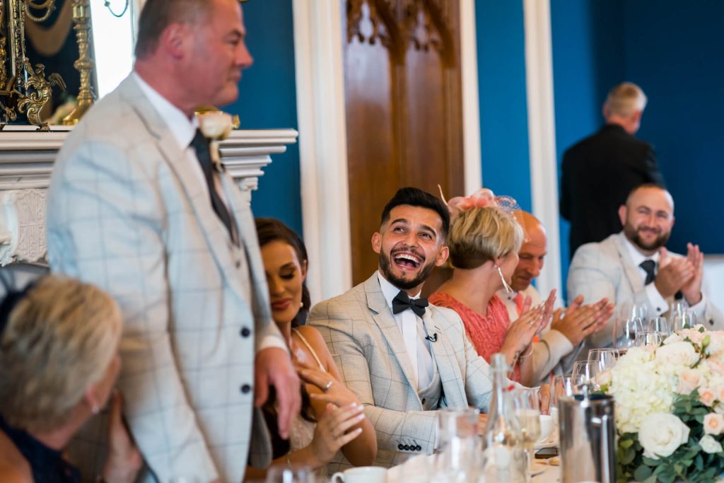 groom lauging and guests clapping