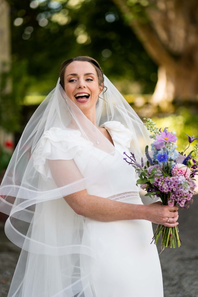 bride holding her bouquet and laughing
