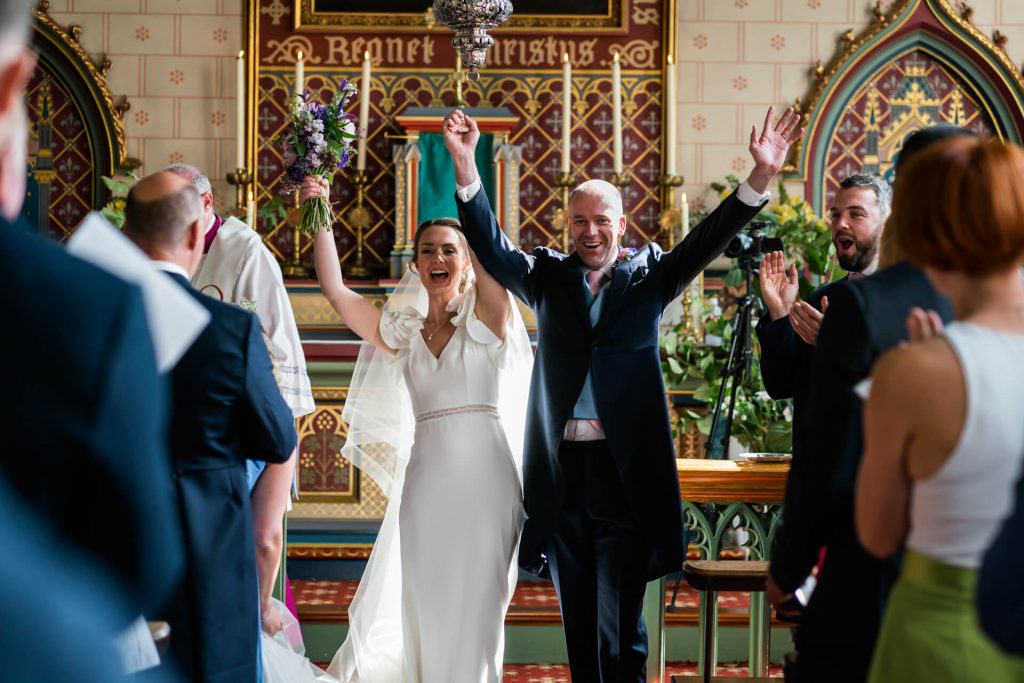 bride and groom celebrating with their arms in the air as their marriage is announced