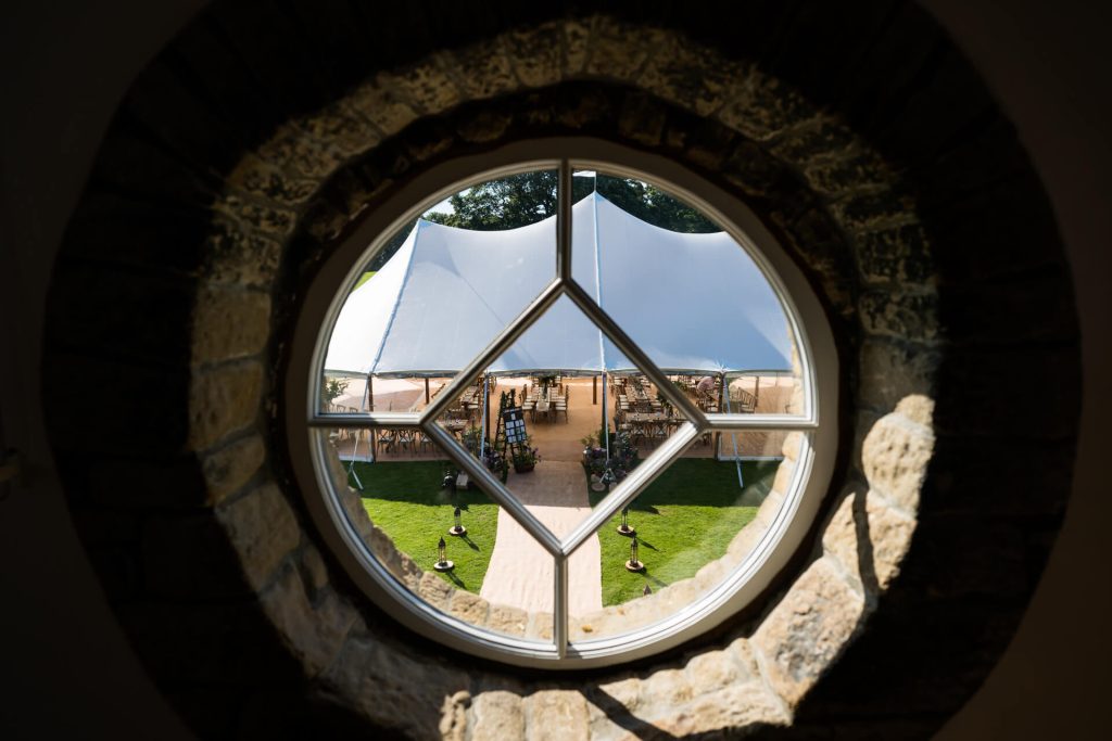 view of the wedding marquee through a porthole window