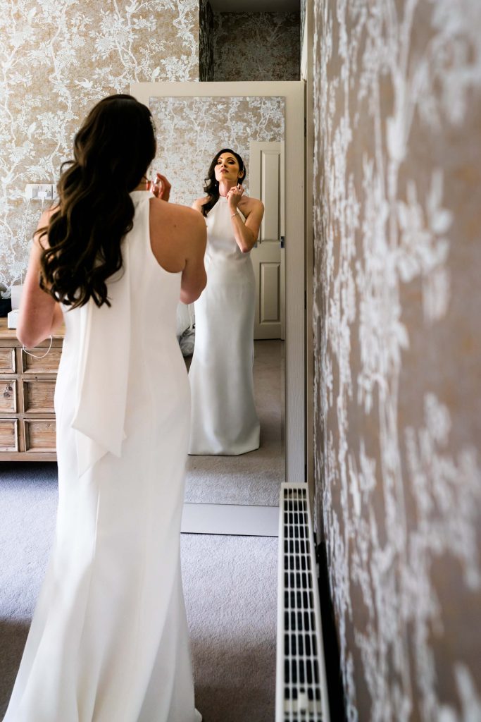 bride looking in a mirror and applying perfume