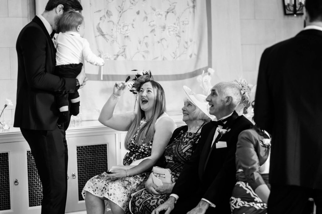 wedding guests laughing with the groom and his baby boy