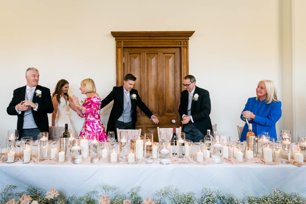 bride and groom walking up to top table as family claps