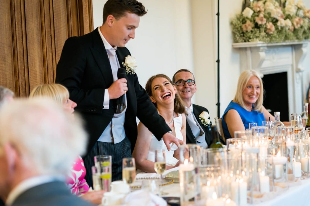bride laughs at the groom as he gives his speech