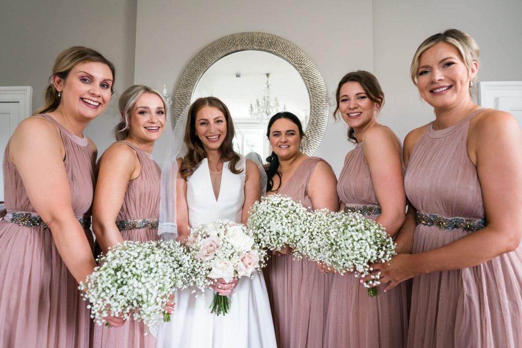 bride and her bridesmaids in their dresses and holding bouquets