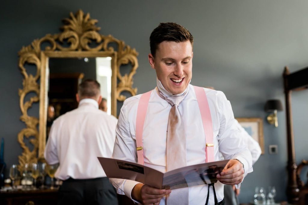 groom smiling whilst reading a card from the bride