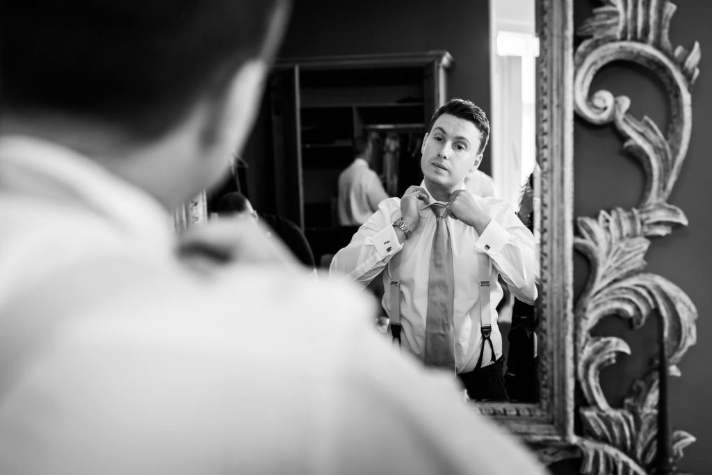 groom fixing his tie in a mirror