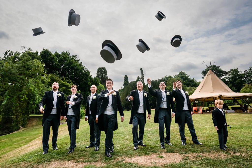 groom and groomsmen throwing their hats in the air
