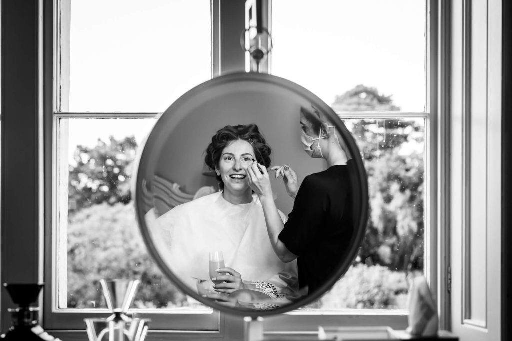 mirror reflection of the bride having her makeup applied